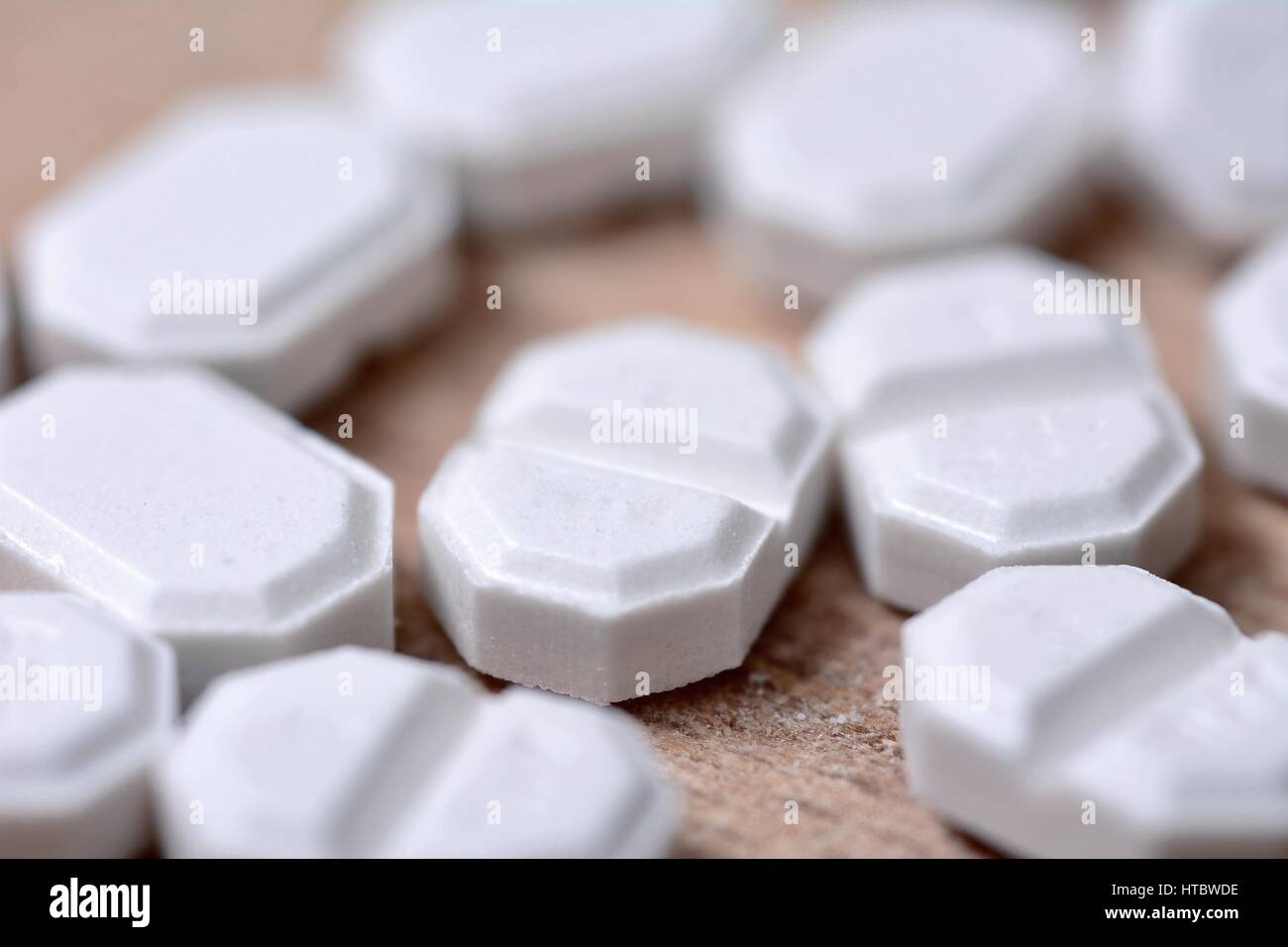 Macro of the white pills on wooden brown background. Stock Photo