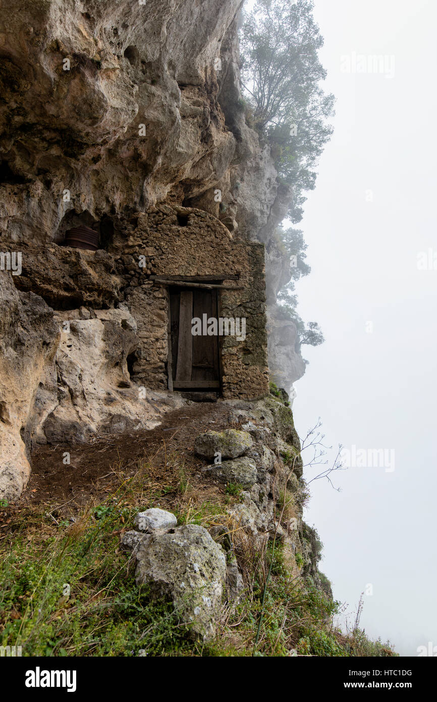 Doorway into a cliff dwelling with fog rolling in Stock Photo
