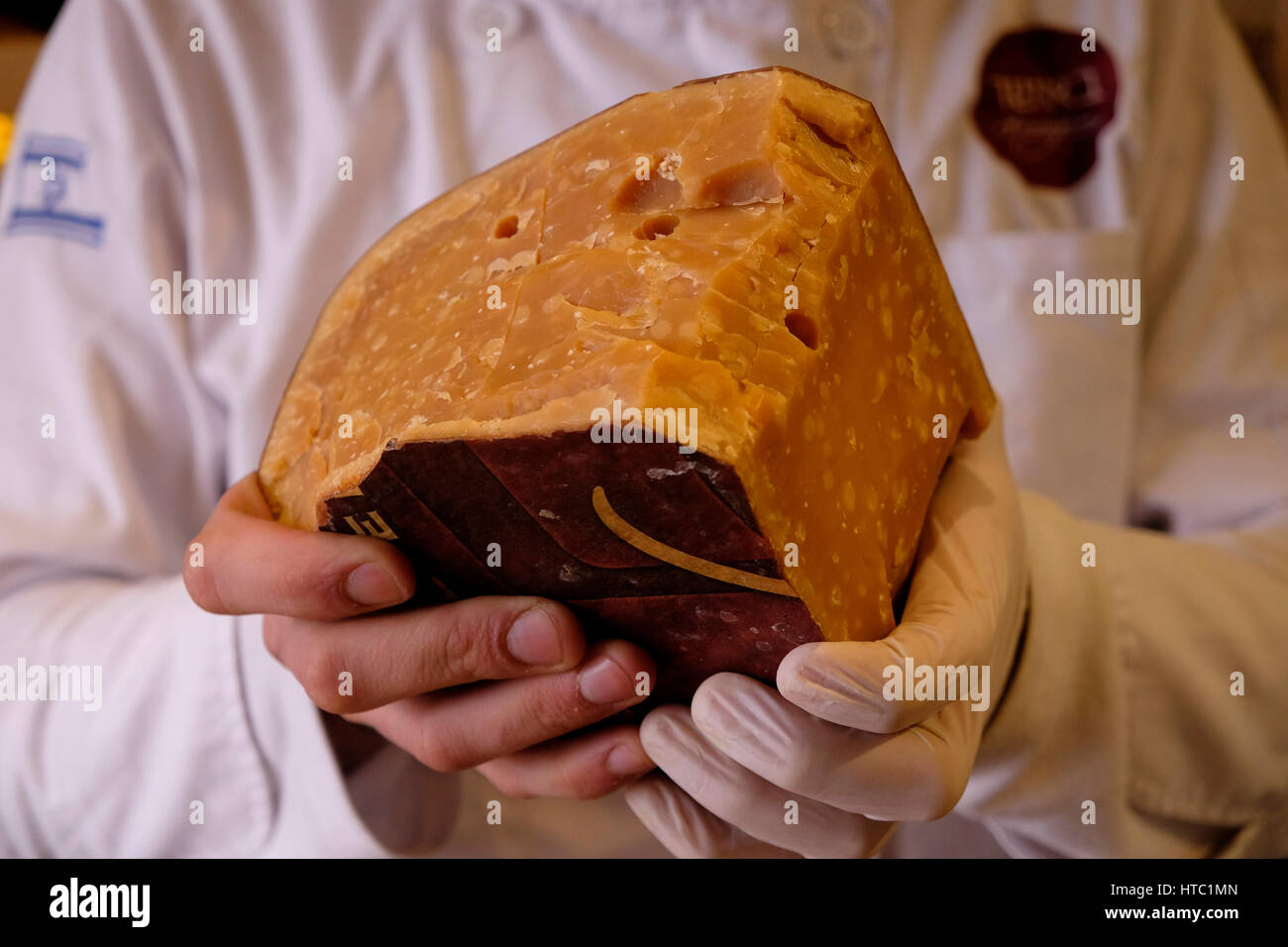 An Israeli cheese monger holding a Vintage Gouda Aged 5 years cheese at