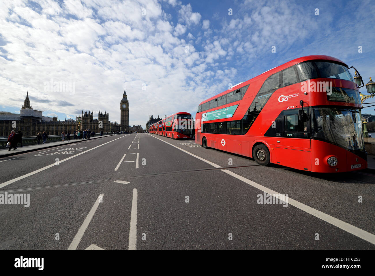 A line of six red New Routemaster London buses on Westminster Bridge, London, UK. Parliament Stock Photo