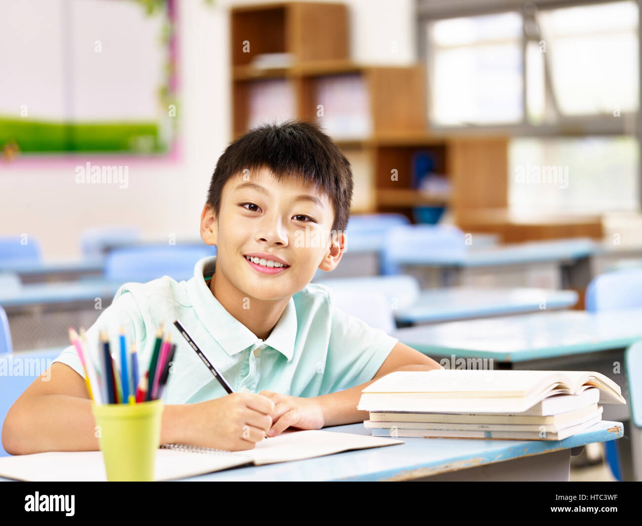 happy asian elementary school boy studying in classroom, looking at camera smiling. Stock Photo