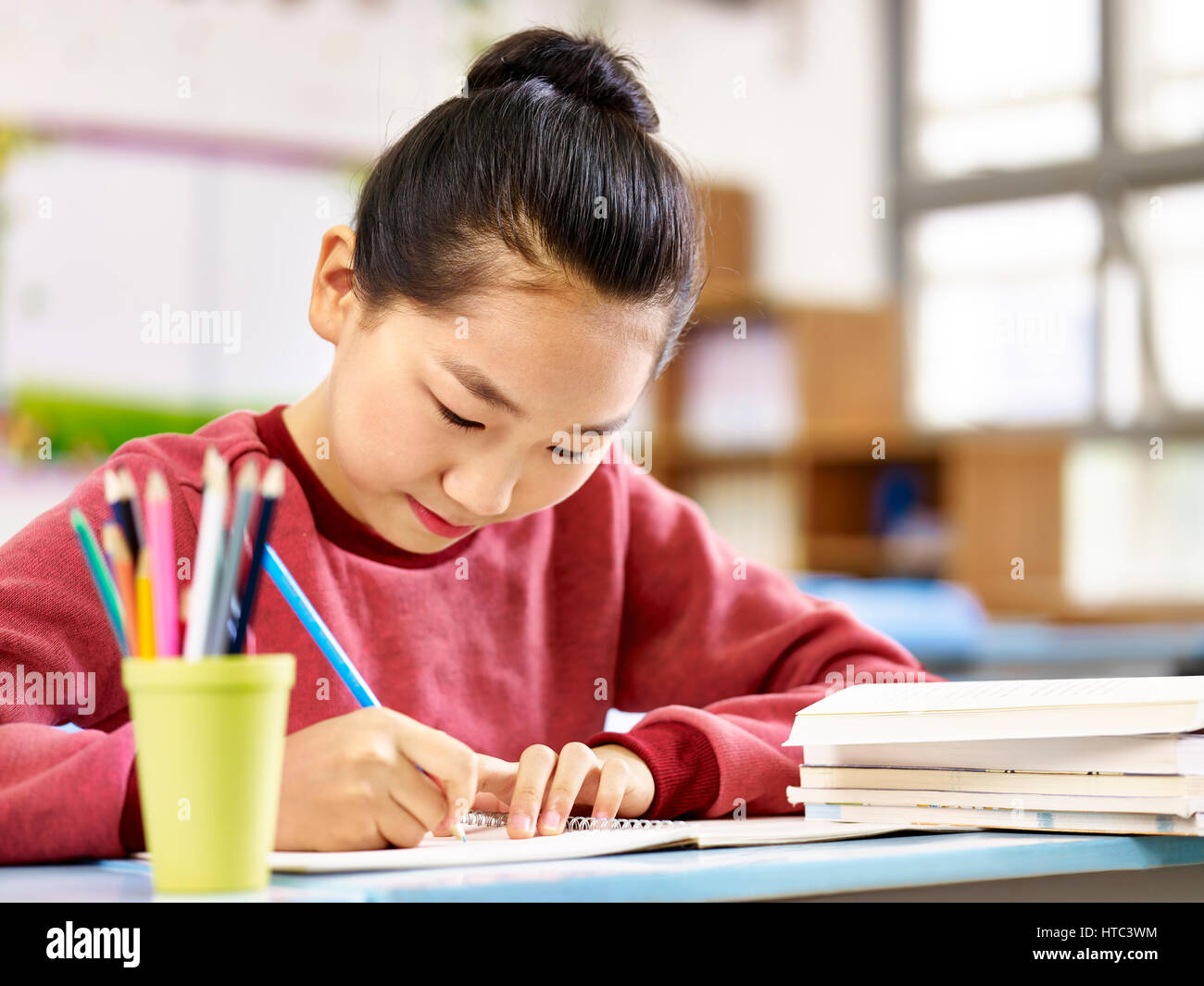 asian primary school student studying or doing homework in classroom. Stock Photo