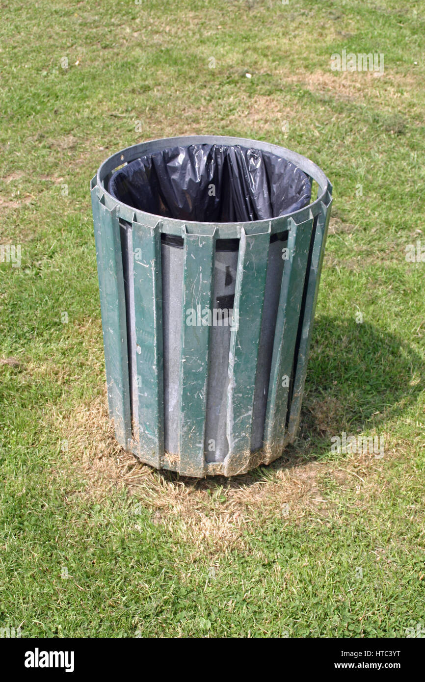 Metal litter bin with green slats containing a black plastic rubbish