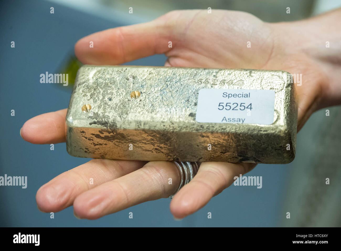 A bar of pure gold melted together from scrap gold bits held by Chris Walne, Lab Manager, at The Goldsmiths' Company Assay Office. London, UK. Stock Photo