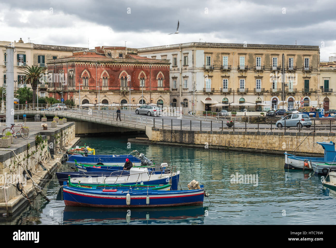 Local fisherman's boats at the marina in Syracuse city, southeast corner of the island of Sicily, Italy. Santa Lucia bridge on background Stock Photo