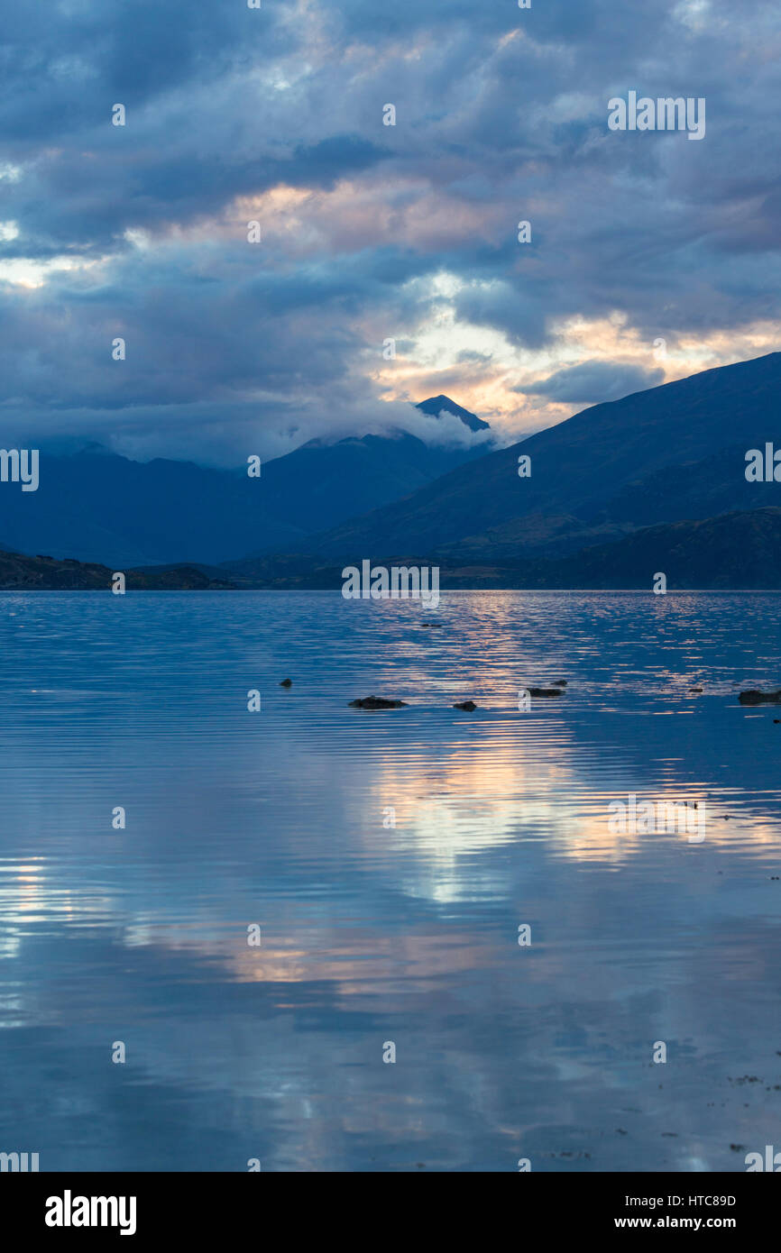 Wanaka, Otago, New Zealand. View across Bremner Bay at dusk, colourful  clouds reflected in the tranquil waters of Lake Wanaka Stock Photo - Alamy