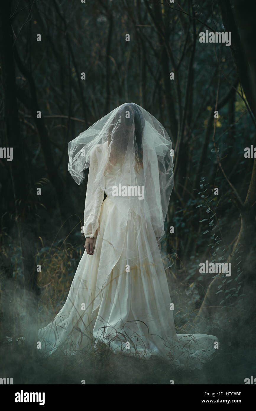 Creepy lone bride in misty woods . Halloween conceptual Stock Photo