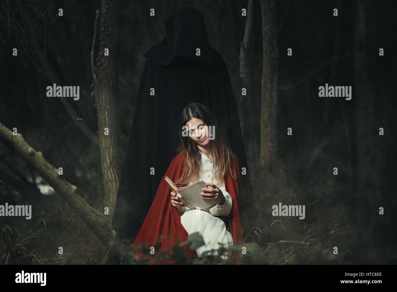 Woman with hooded figure at her back . Halloween and horror Stock Photo