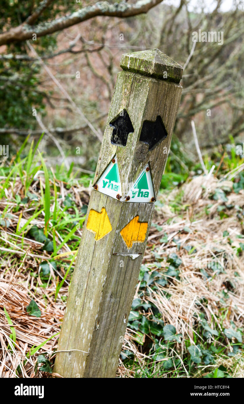 A Youth Hostel Association (YHA) and black and yellow direction arrows on a footpath wooden sign post Stock Photo