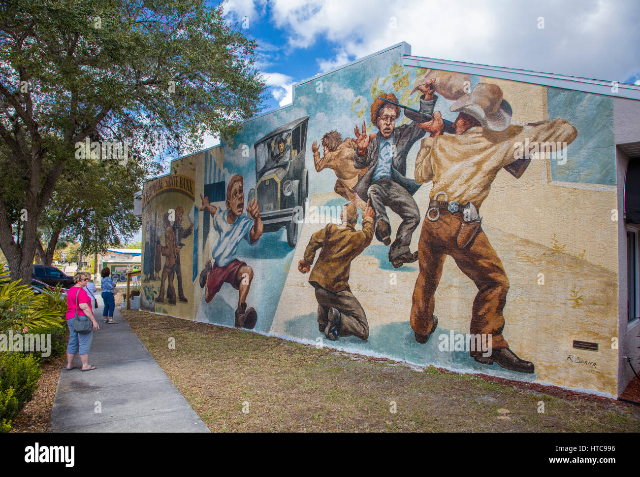 People looking at art murals painted on outdoor building walls in Lake
