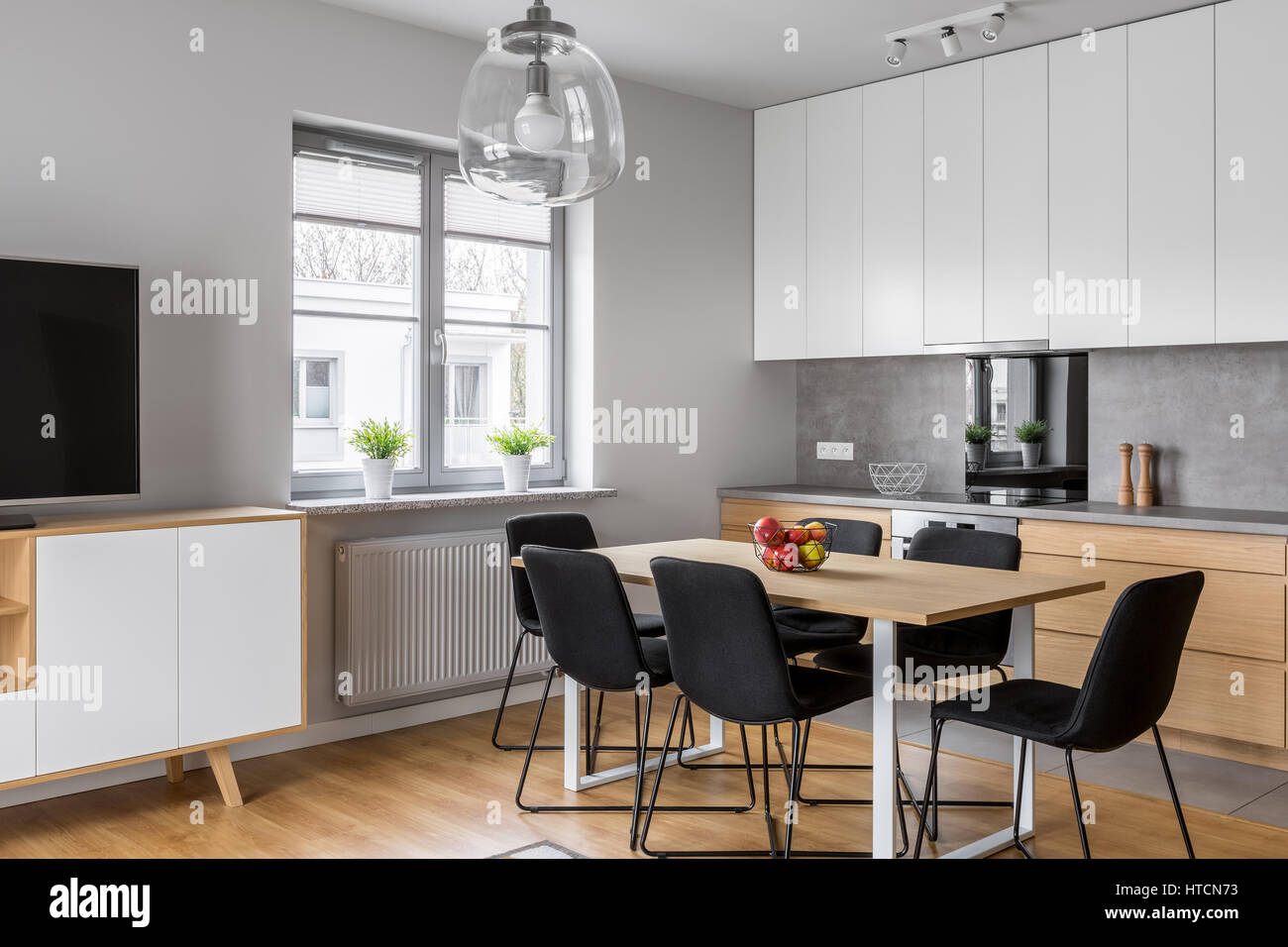 Minimalist, contemporary kitchen with dining room and tv screen Stock