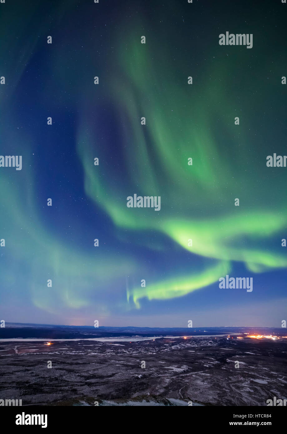 The aurora borealis glows over the Delta River and the distant lights of Fort Greely and Delta