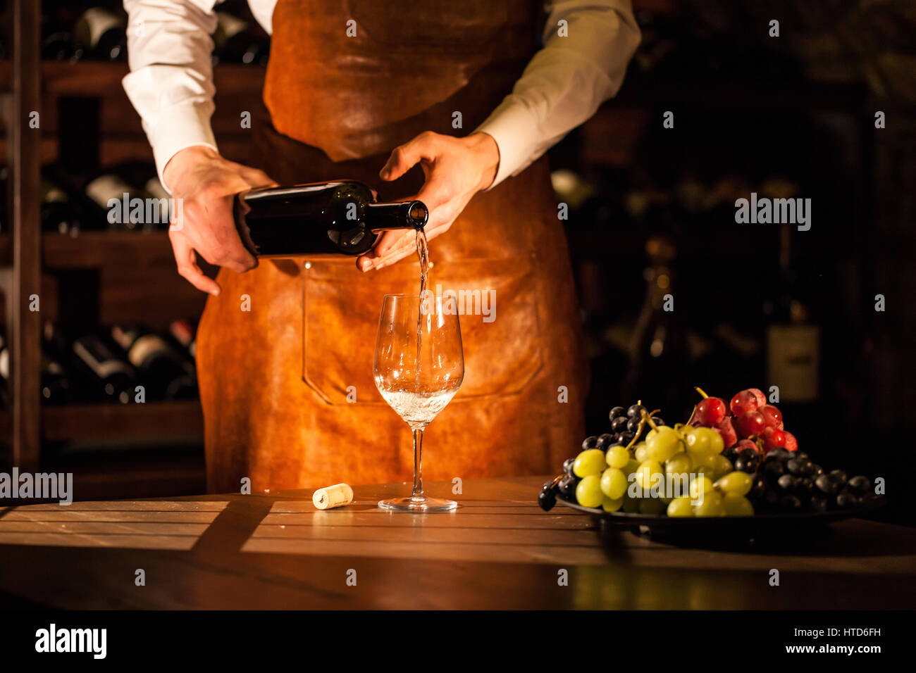 Sommelier pouring wine from a bottle into a glass. Composition of