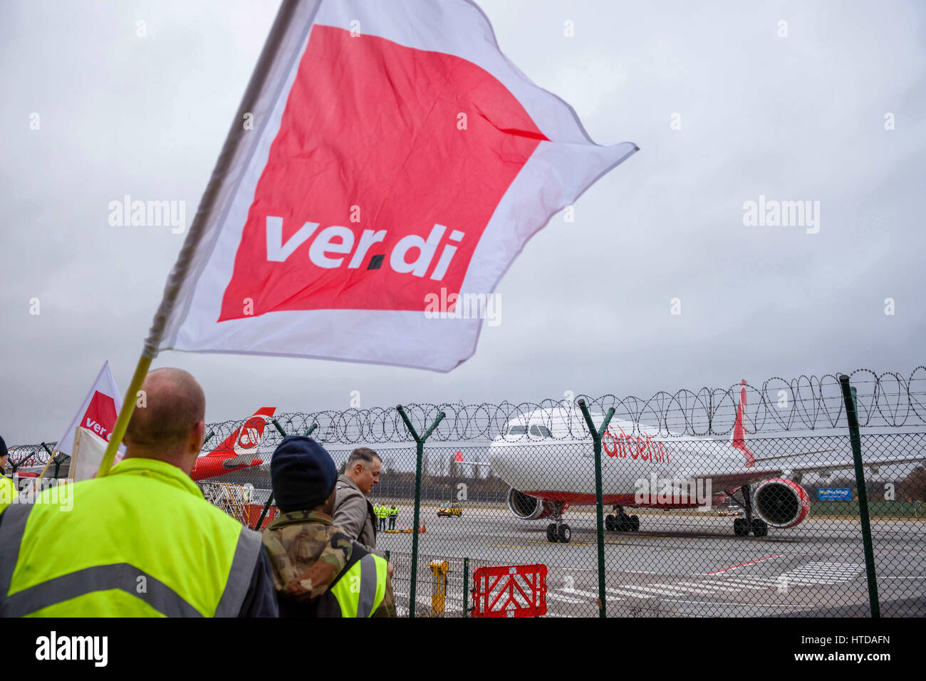 Berlin, Germany. 10th Mar, 2017. Ground staff hold up flags near the runway at Tegel Airport in Berlin, Germany, 10 March 2017. German trade union Verdi had called on some 2,000 ground staff to join the strike. The strike began on 10 March 2017 at 03:00 GMT and is to end on 11 March 2017 at 04:00 GMT. The main reason for the strike is the ongoing labour dispute between Verdi and the Forum of Ground Transport Service Providers in which the companies operating at the airports are organized. The trade union is demanding a pay rise for ground staff. Photo: Gregor Fischer/dpa/Alamy Live News Stock Photo
