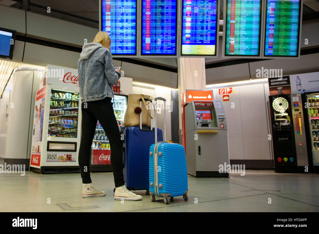 A traveller with two suitcases standing in front of a display board in the terminal building at Tegel Airport in Berlin, Germany, 10 March 2017. German trade union Verdi had called on some 2,000 ground staff to join the strike. The strike began on 10 March 2017 at 03:00 GMT and is to end on 11 March 2017 at 04:00 GMT. The main reason for the strike is the ongoing labour dispute between Verdi and the Forum of Ground Transport Service Providers in which the companies operating at the airports are organized. The trade union is demanding a pay rise for ground staff. Photo: Gregor Fischer/dpa Stock Photo
