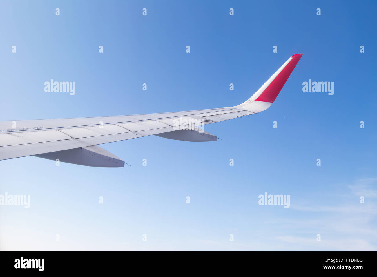 Wing of an airplane flying above the blue sky and clouds Stock Photo ...