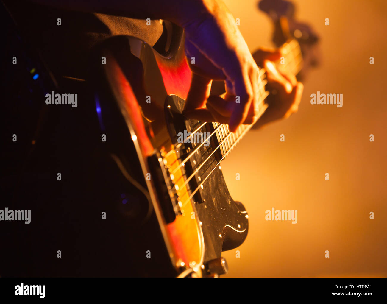 Close-up photo of bass guitar player, soft selective focus, live rock music theme Stock Photo
