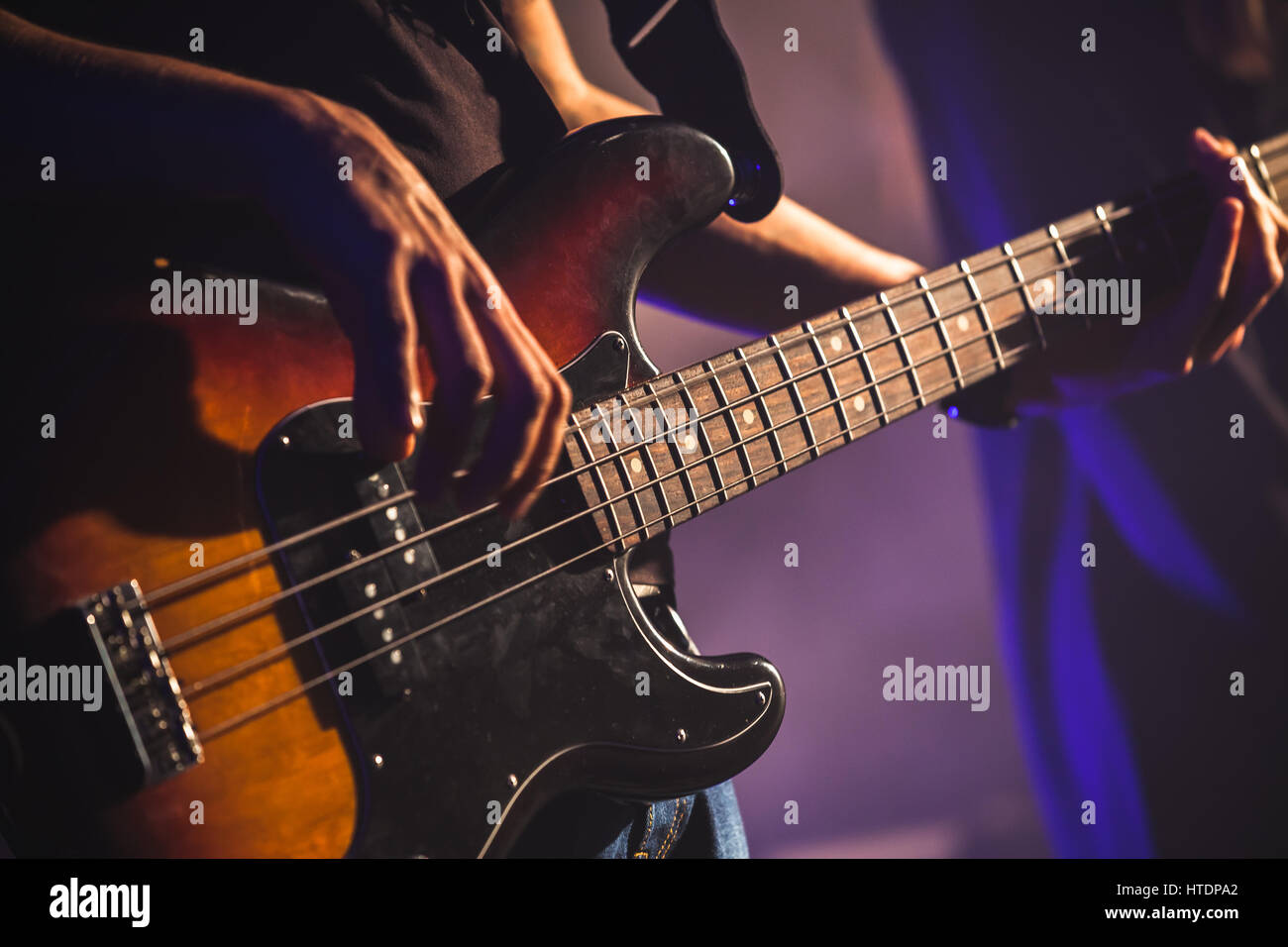 Close-up photo of bass guitar player hands, soft selective focus, live rock music theme Stock Photo
