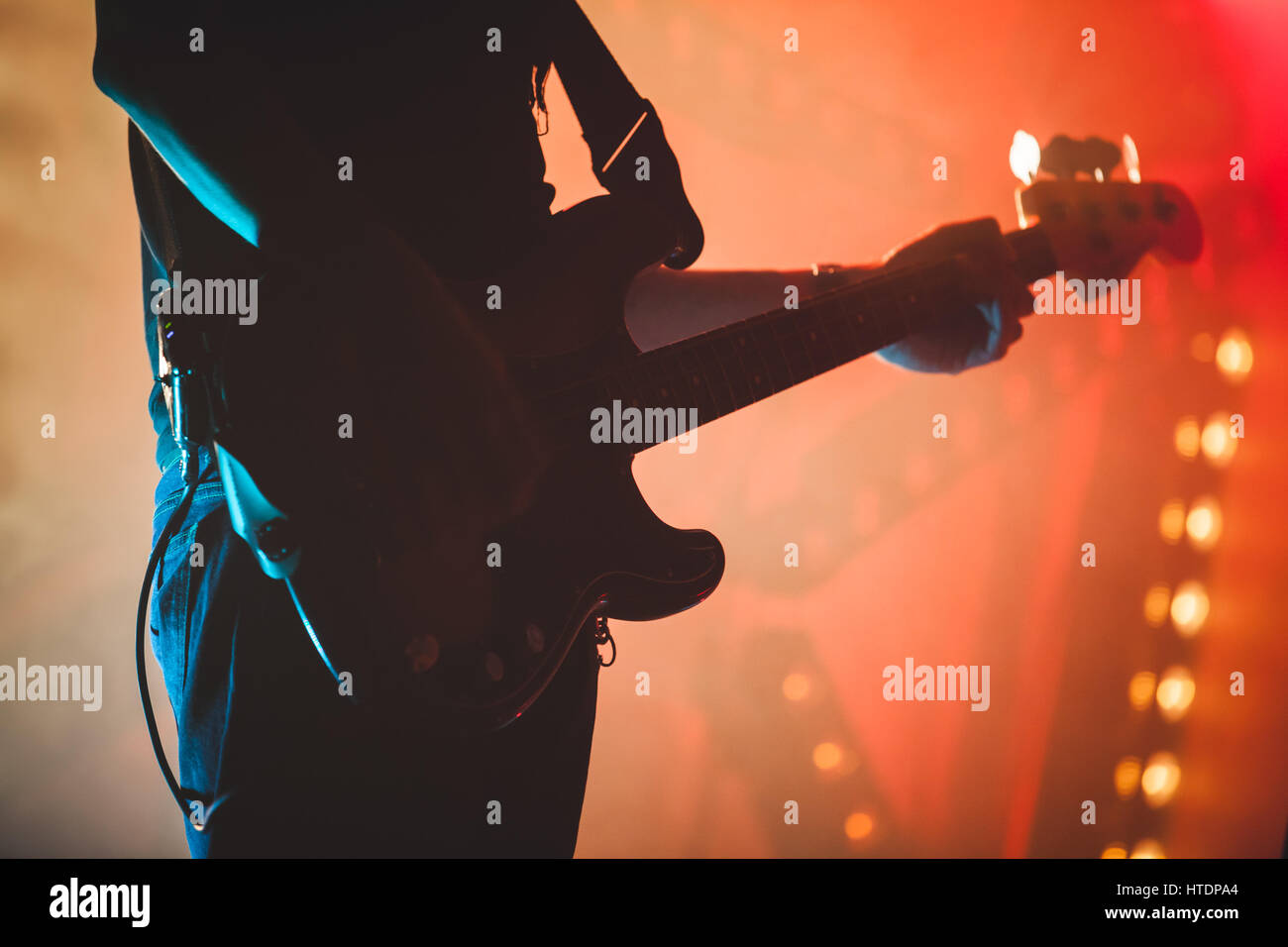 Silhouette of bass guitar player with colorful stage illumination, live rock music theme Stock Photo