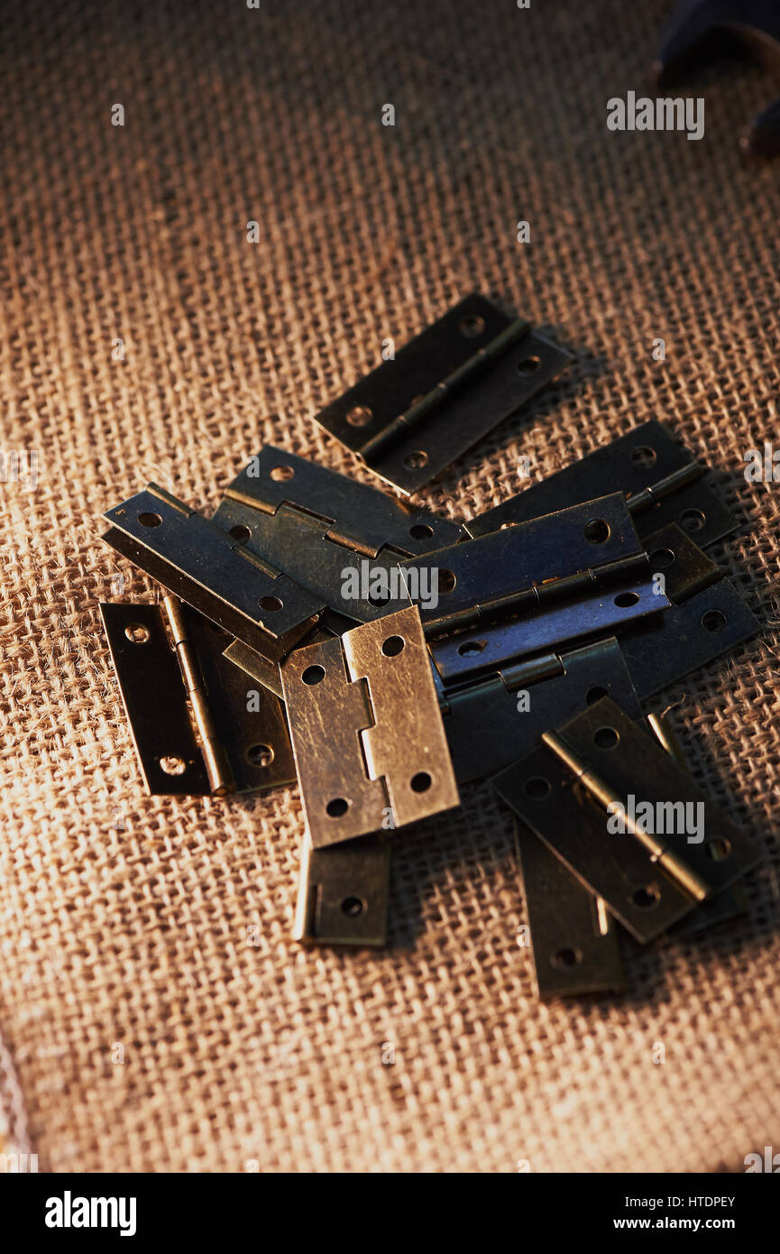 Door hinges made of dark metal on a dark background of burlap. The