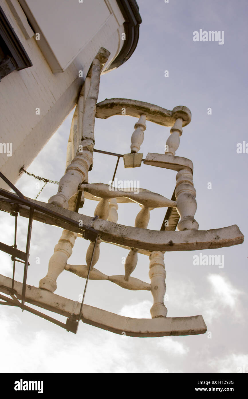 A hanging rocking chair above a store front sets a stark contrast to the blue sky in Camden Town, London Stock Photo