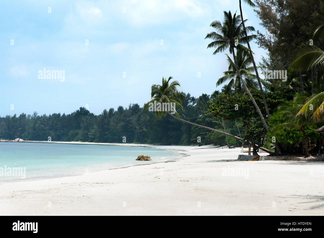 Tropical white sand beach and palm trees stretching out towards the blue colored ocean in the afternoon at Tanjung Pinang on Bintan island, Indonesia. Stock Photo