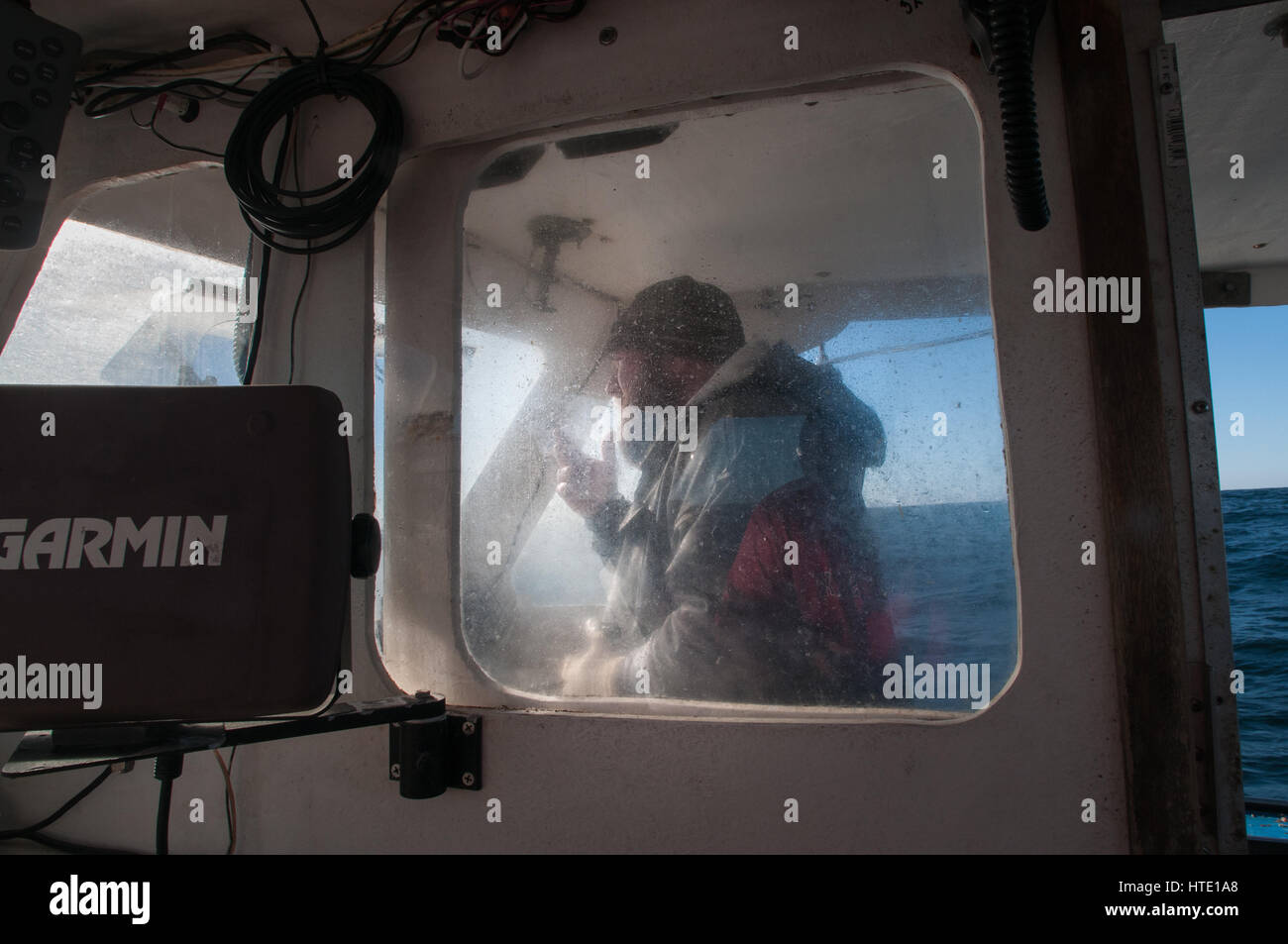 Captain drives lobster boat to fishing grounds Stock Photo