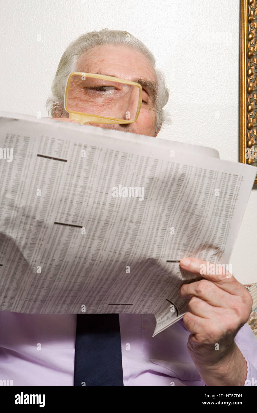 Man reading newspaper with magnifying glass Stock Photo Alamy