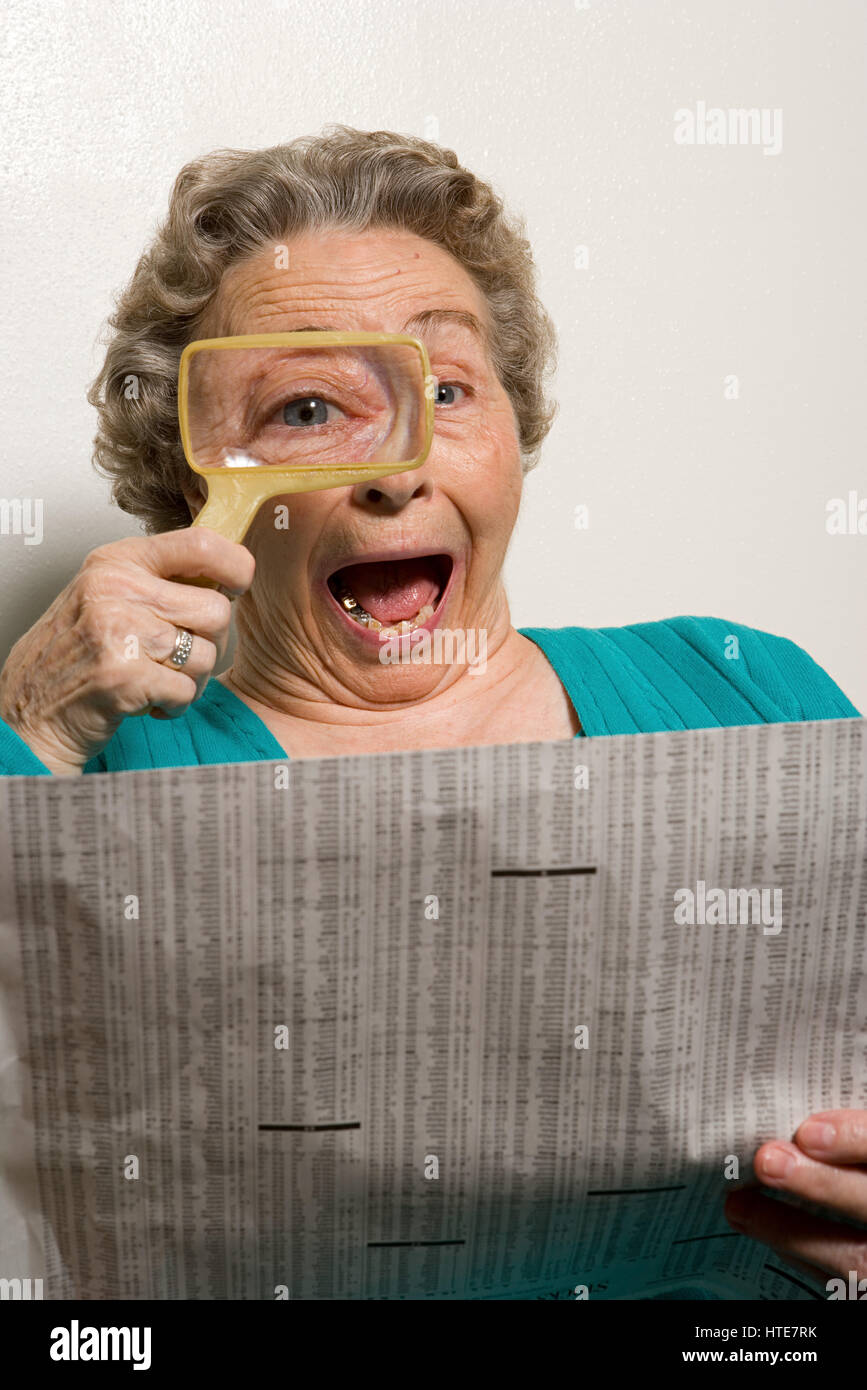 Woman reading newspaper with magnifying glass Stock Photo Alamy
