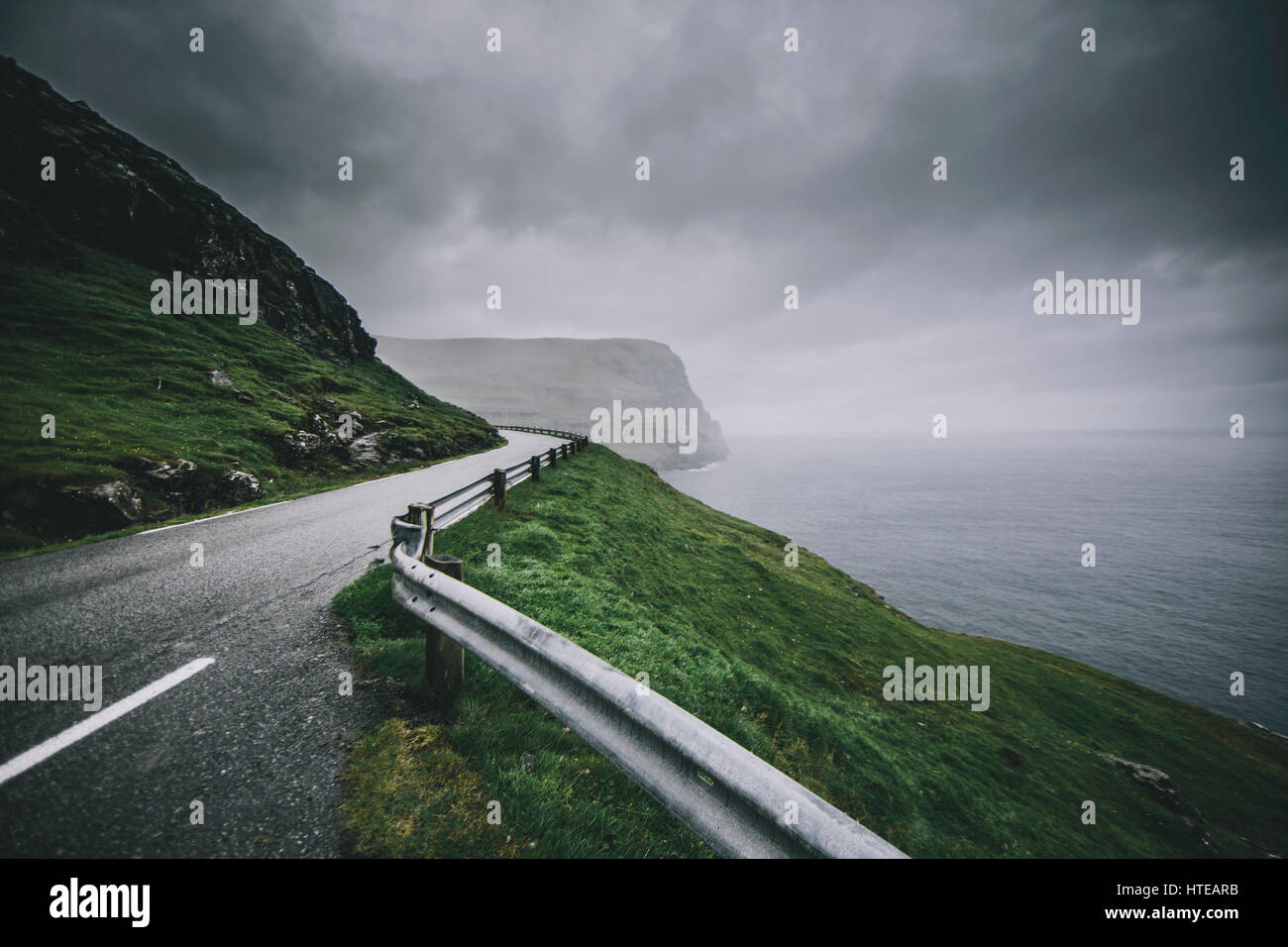 Road leading to the beautiful mountainous landscape of the Faroe Islands. Stock Photo