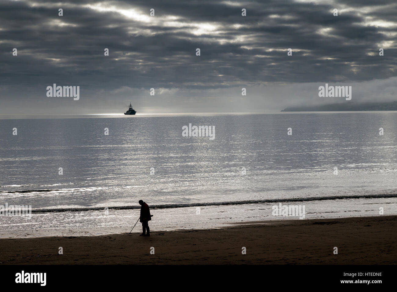 Metal detectorist on Paignton Beach treasure hunting,a naval vessel
