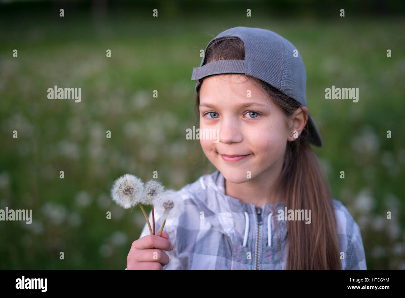 happy child girl holding three dandelions outdoor look to camera Stock Photo