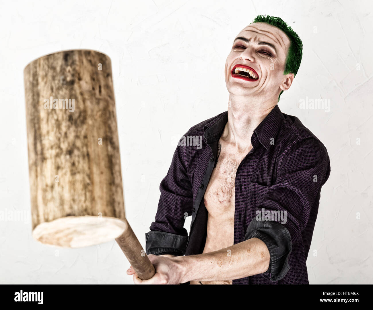 guy with crazy joker face, green hair and idiotic smile. carnaval costume.  holding hammer for cricket Stock Photo - Alamy