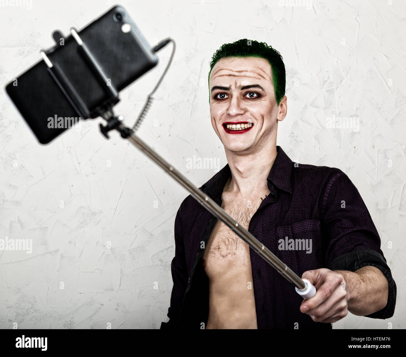 guy with crazy joker face, green hair and idiotic smile. carnaval costume.  making selfy photo Stock Photo - Alamy