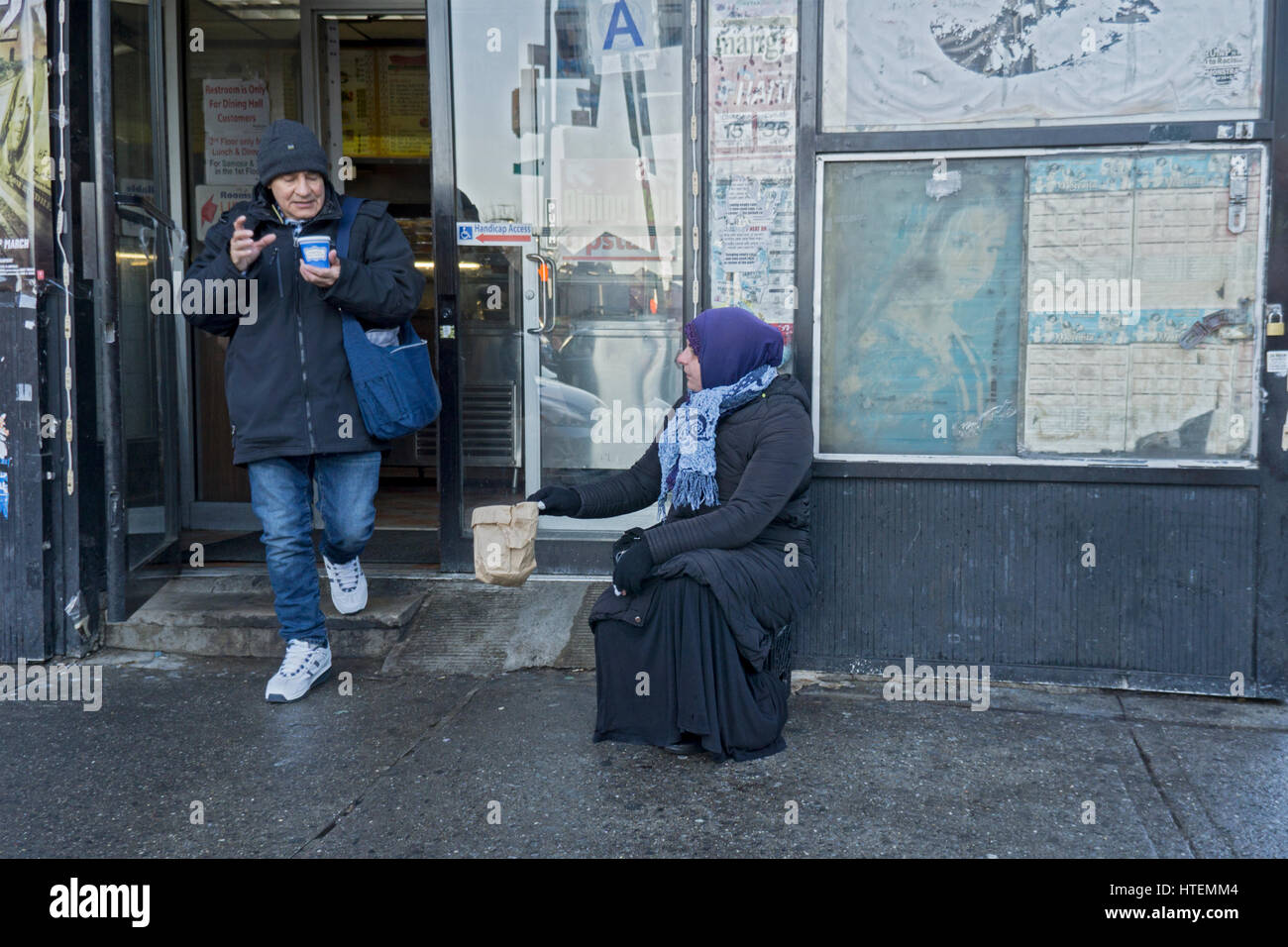 A poor Muslim woman asking for donations outside a food shop in Jackson Heights, Queens, New York City. Stock Photo