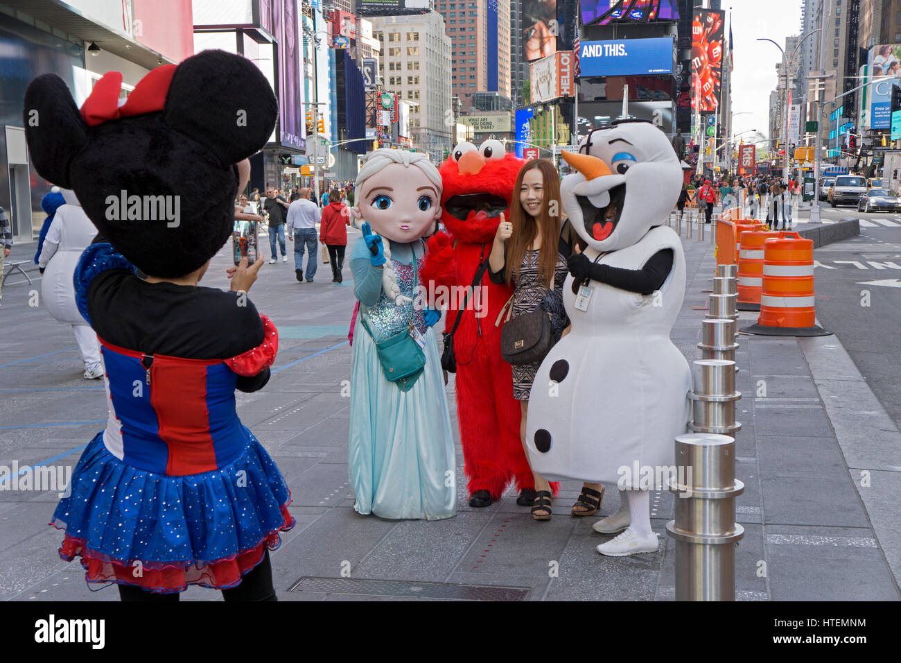 An Asian tourists poses for photos with buskers dressed like comic book and television characters. Times Square, New York City. Stock Photo
