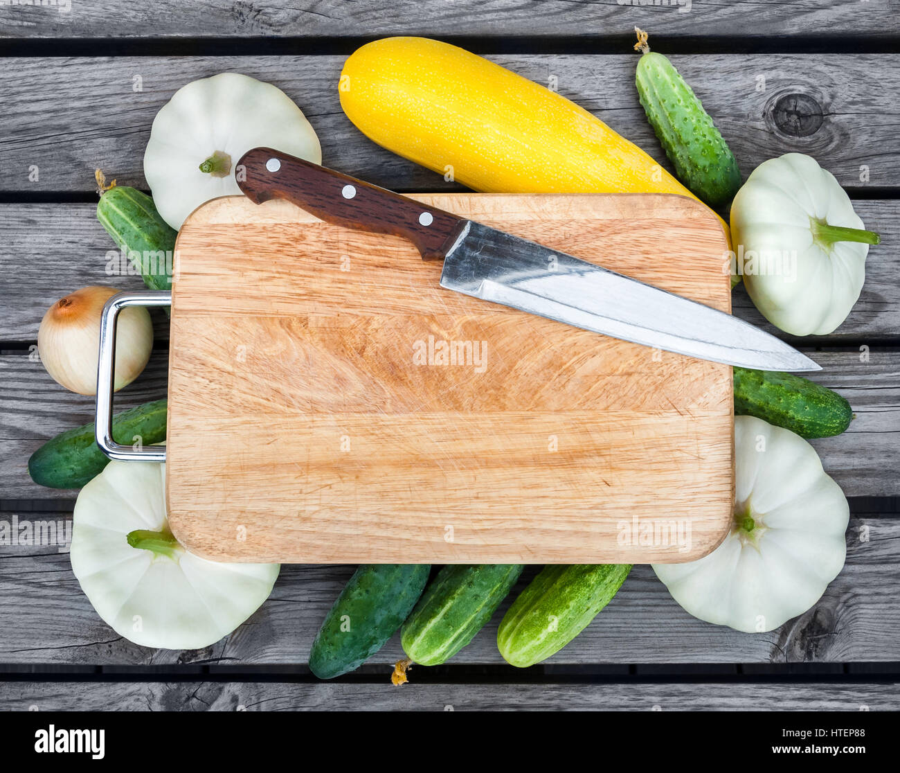 Cutting board, knife, fresh vegetables on wooden table. Top view with
