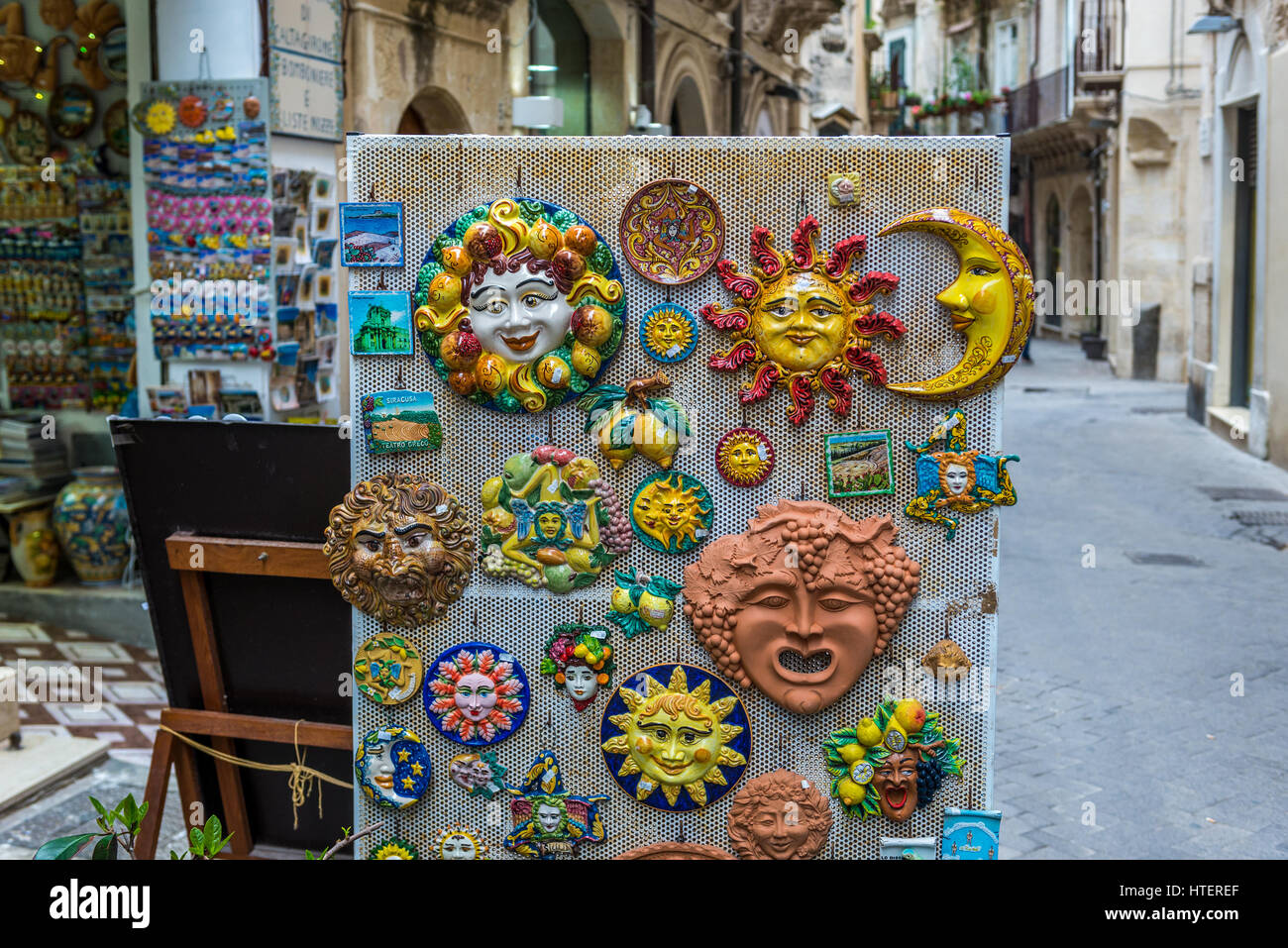 Travel magnets - masks, sun dishes and Trinacria symbols for sale on the Ortygia island, historical part of Syracuse city, southeast corner of the isl Stock Photo