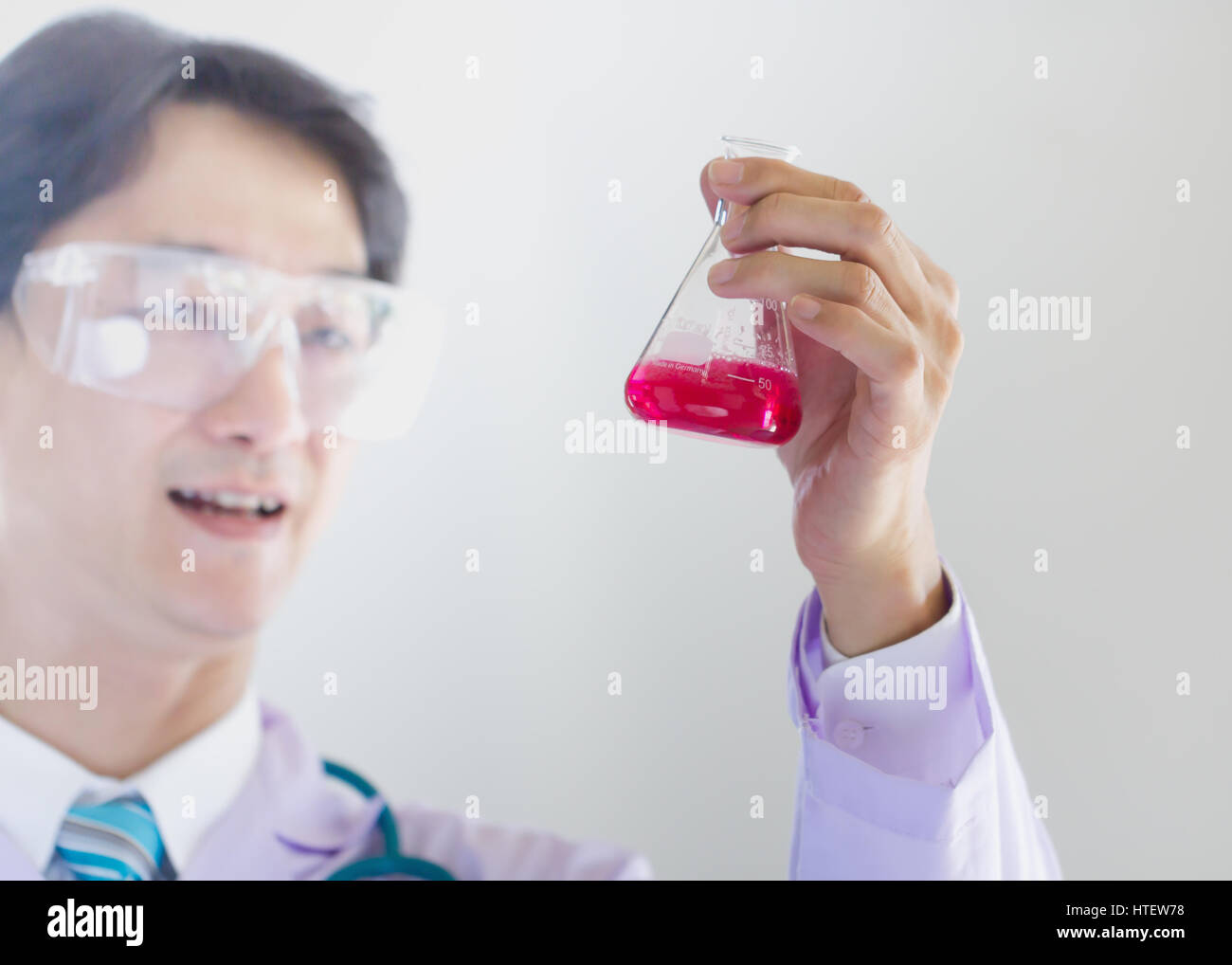 Investigator checking test tubes. Man wears protective goggles Stock Photo