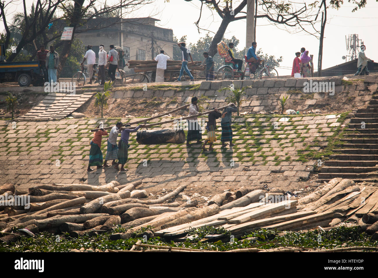 DHAKA, BANGLADESH - FEBRUARY 2017: Men carrying wood on the banks of the river in Dhaka, Bangladesh Stock Photo