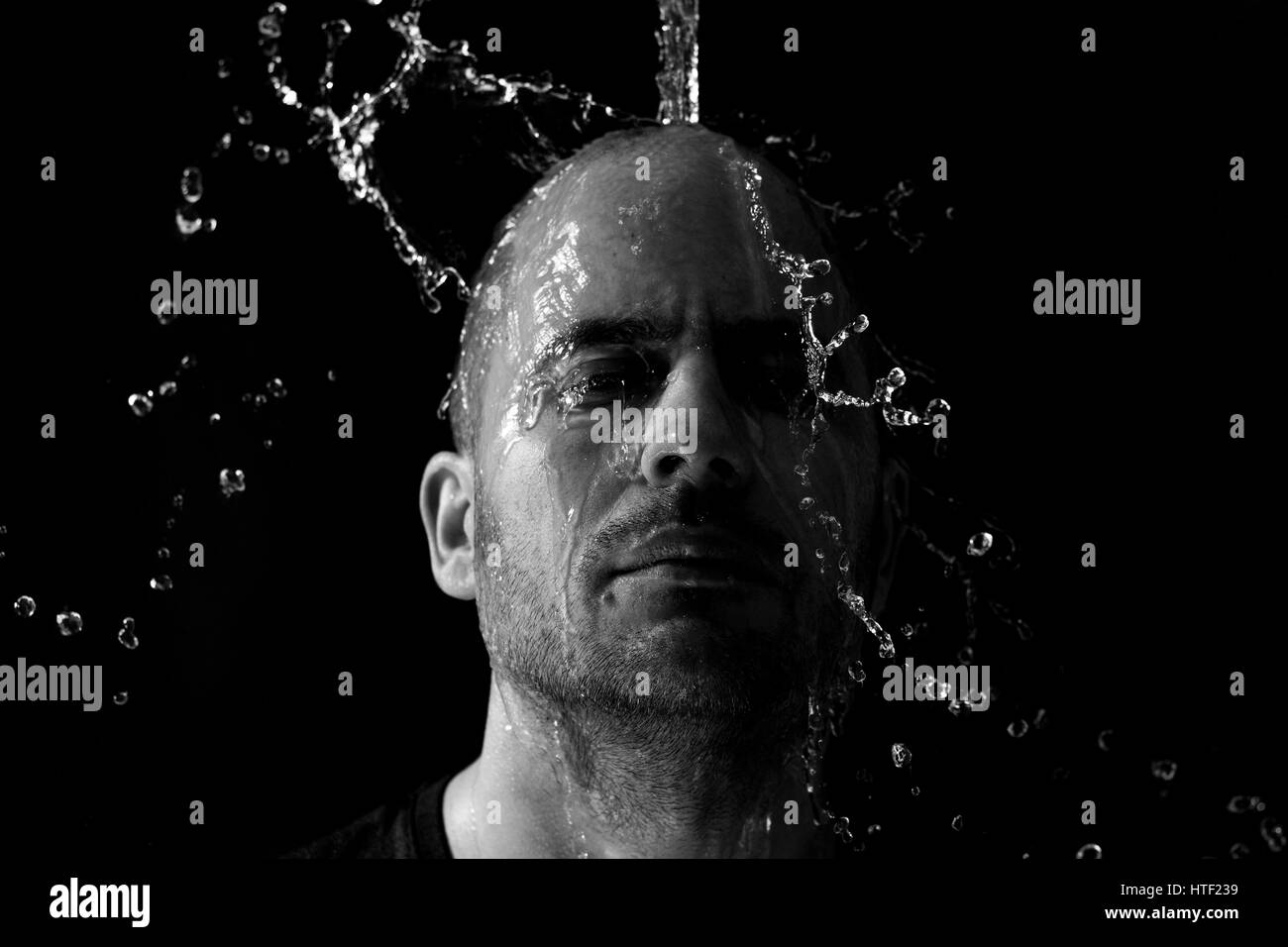 Portrait of a man being thrown water in the face against a black background Stock Photo