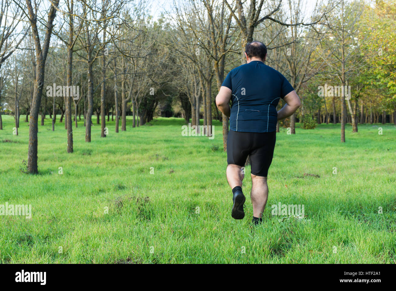 Big belly man jogging , exercising, doing cardio in the park , slightly