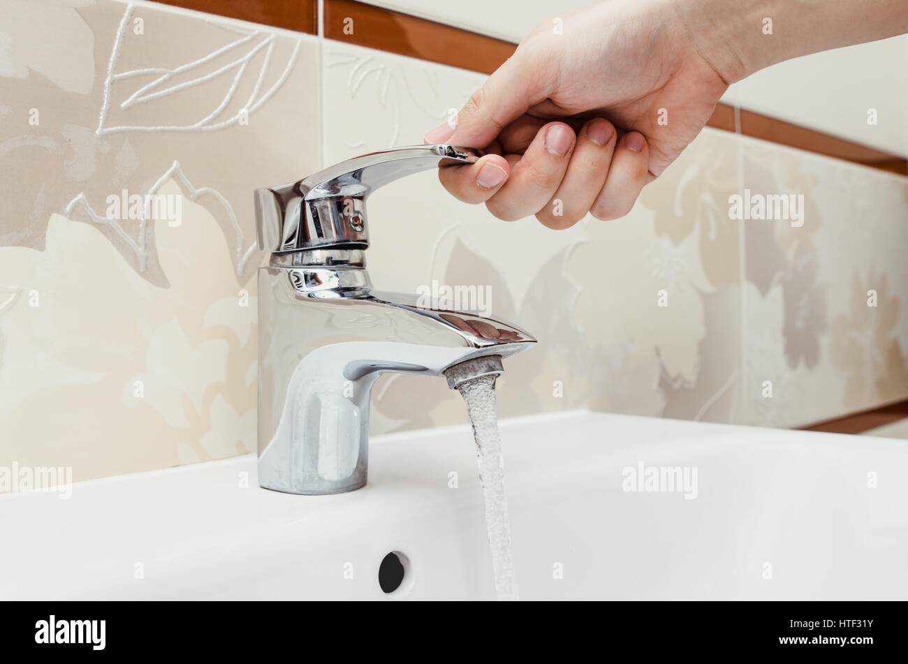 Man unscrew the faucet in the bathroom. Utilities water bill cost rise