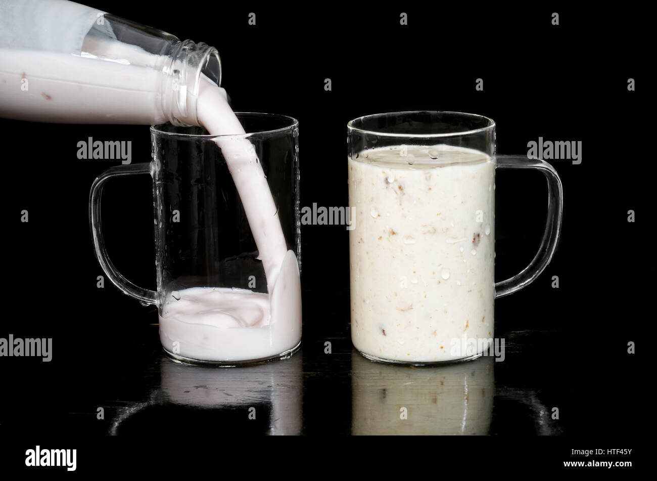Different types of yogurt, poured in a glass Cup. Reflection on black