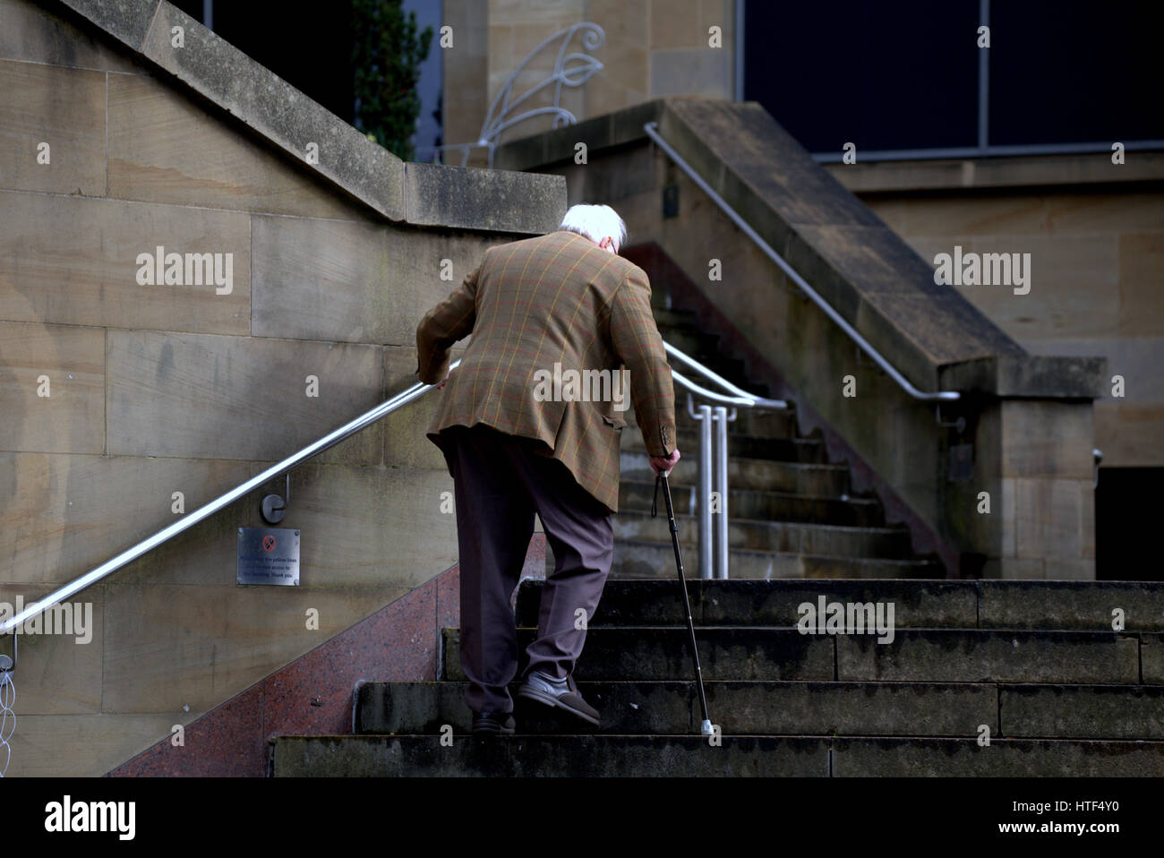 old man with white grey hair  walking stick climbing stairs Stock Photo