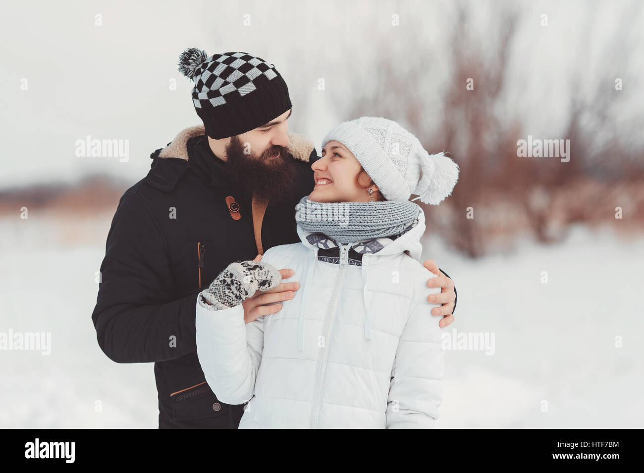 A romantic couple in warm trendy clothes look at each other and smile ...