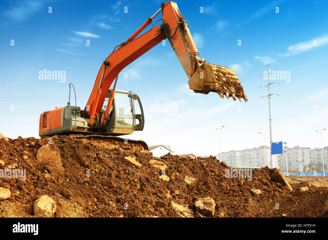 Yellow excavator on a construction site against blue sky Stock Photo ...
