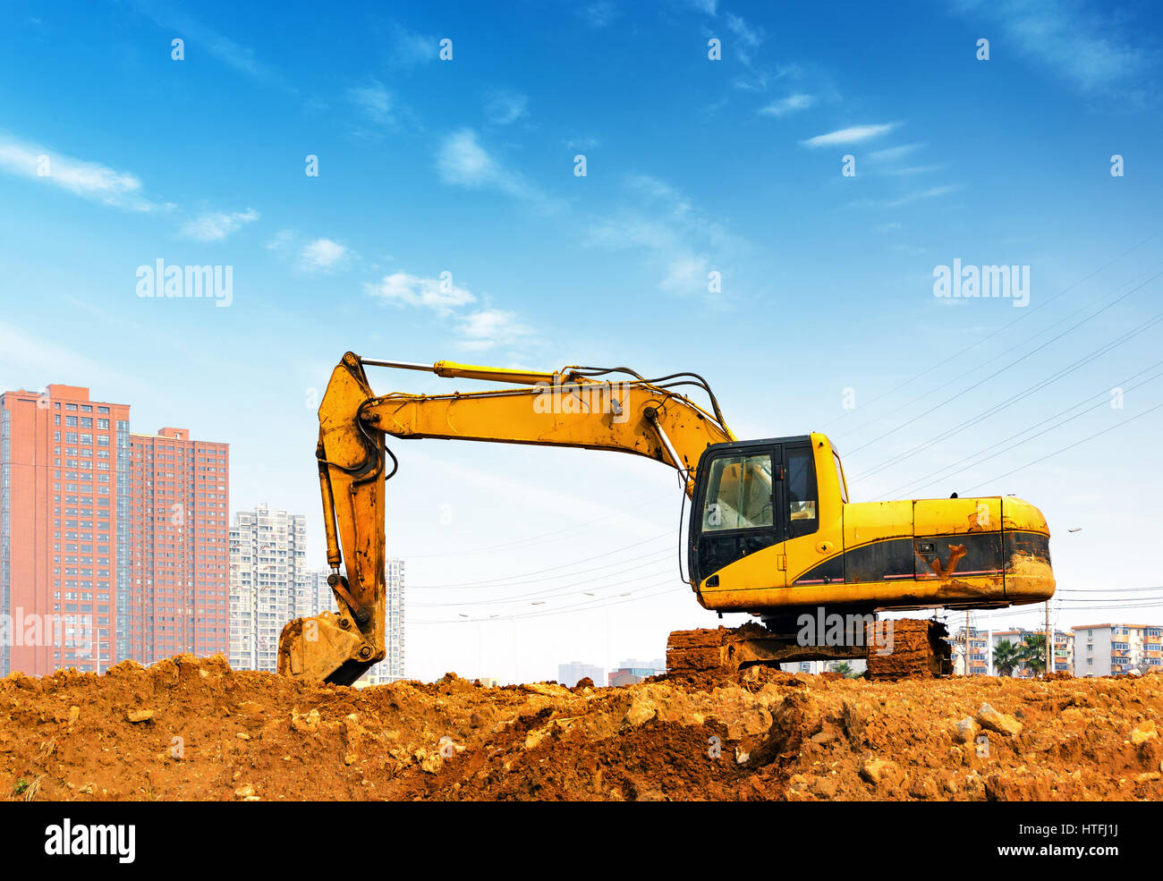 Yellow excavator on a construction site against blue sky Stock Photo ...