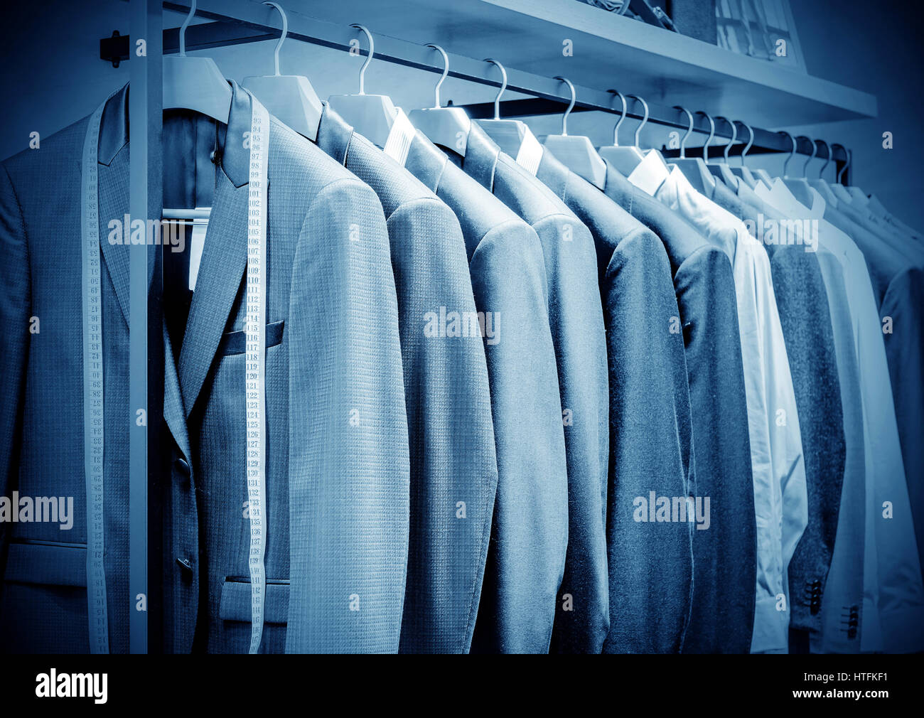 Row of men's suits hanging in closet. Stock Photo