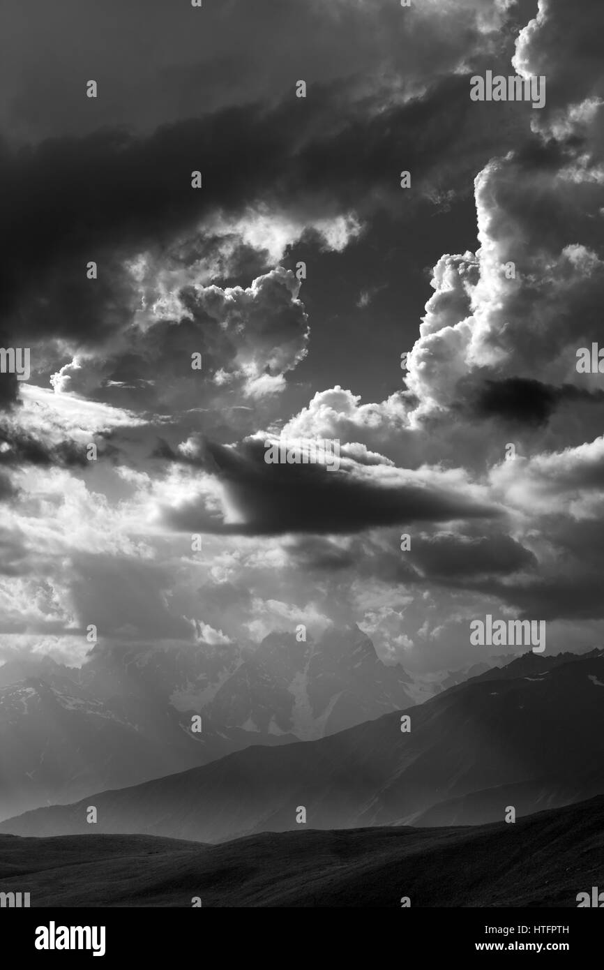 Black and white view on mountains in sunlight clouds. Caucasus Mountains. Georgia, region Svaneti. Stock Photo
